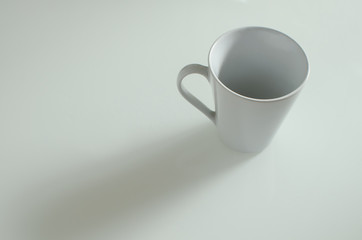 white cup casting a long shadow on a neutral table