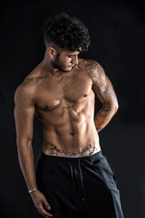 Young athletic man with tattoo isolated on black