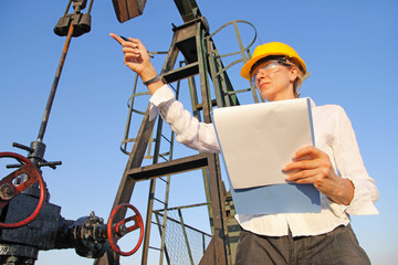 Female engineer writing on clipboard in oil field