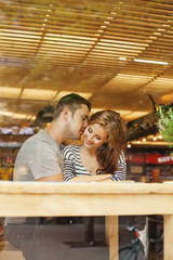 lovely couple sitting indoors in cafe (view through the glass)