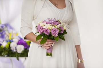 Obraz na płótnie Canvas beautiful wedding bouquet of purple roses in the hands of the br