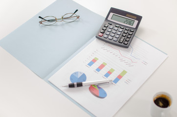 Business graphs with a calculator, a pen and glasses