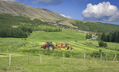 Green meadow with a tractor in high mountains