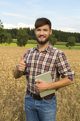 Young farmer at his corn field, thumb up