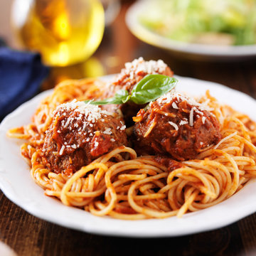 spaghetti and meatballs at cluttered dinner table
