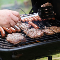 turning food on grill with haumbers and hotdogs