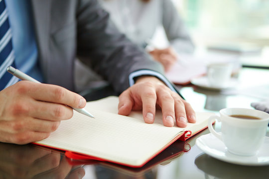 Hand with pen and notepad