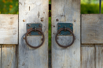 Wooden gate with rusty old iron knockers