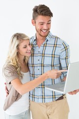 Obraz premium Happy attractive young couple using laptop
