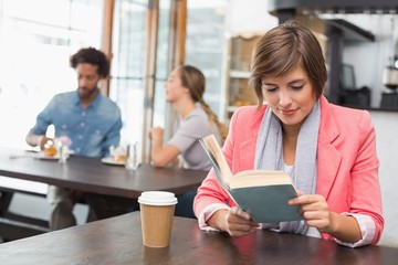 Pretty brunette enjoying her coffee with a book