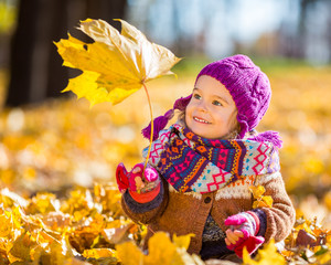 Little girl playing with autumn leaves
