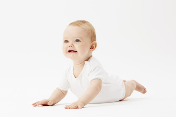 Young baby girl crawling on front, studio.