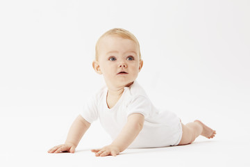 Young baby girl crawling on front, studio.