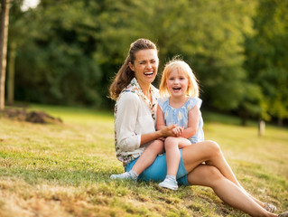 Fototapeta premium Portrait of happy mother and baby girl sitting outdoors
