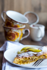 apple strudel on a white plate, cup, .dark background