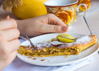 apple strudel on a white plate, hands, eating process