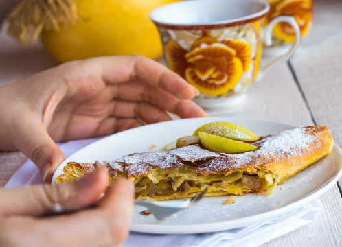 apple strudel on a white plate, hands, eating process