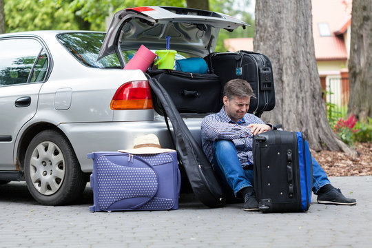 Powerless father next to car trunk