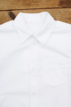 White short sleeved shirt against wooden wall.