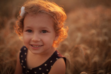 Smiling happy little girl on the wheat field