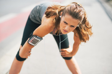 Portrait of tired fitness young woman outdoors in the city 