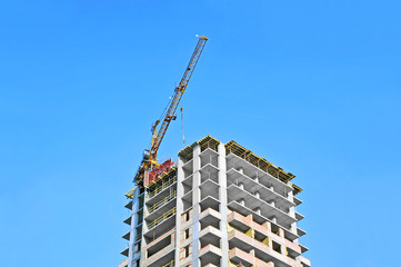 Fototapeta premium Crane and building construction site against blue sky