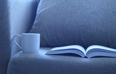 Open book with a cup of cofee on  bed