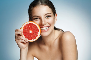 Smiling girl with grapefruit cut in half fruit in hand