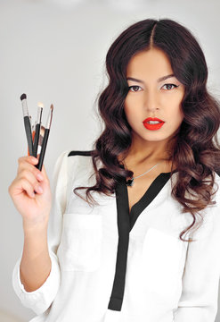 Portrait of a beautiful woman with makeup brushes near face