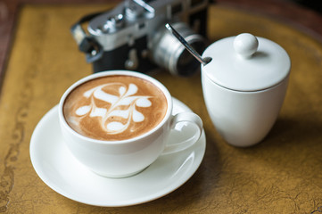 A cup of coffee with flower pattern in a cup on vintage leather