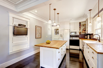 White kitchen with wooden counter top island and TV