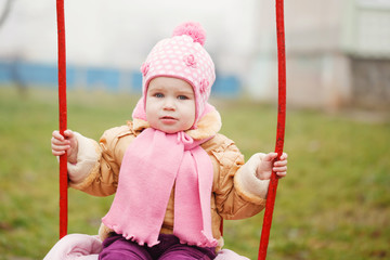 Adorable girl having fun on a swing on autumn day