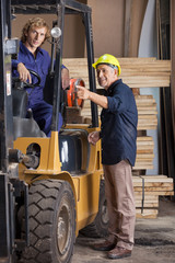 Carpenter Showing Something To Colleague In Forklift