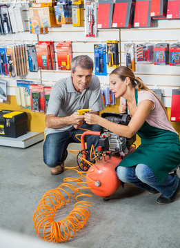 Saleswoman Assisting Customer In Using Air Compressor