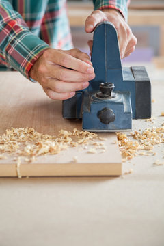 Carpenter's Hands Using Electric Planer On Wood