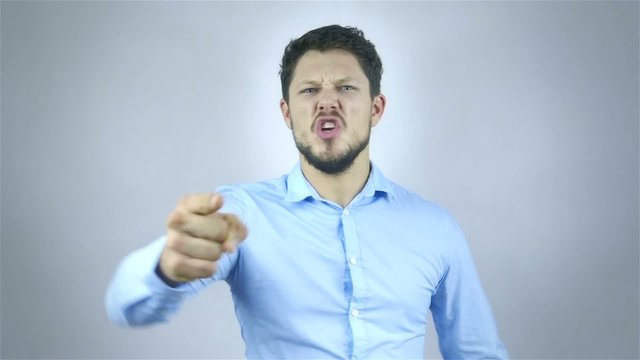 Portrait Of Angry Young Man Shouting Over Grey Background