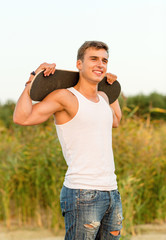 Fototapeta premium smiling teenage boy with skateboard outdoors