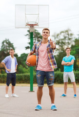 group of smiling teenagers playing basketball