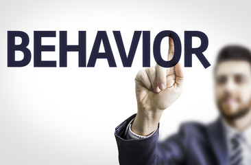 Business man pointing to transparent board with text: Behavior