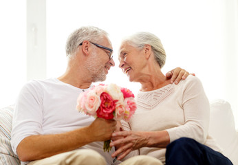 happy senior couple with bunch of flowers at home