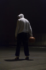Hooded basketball player holding a ball in one hand