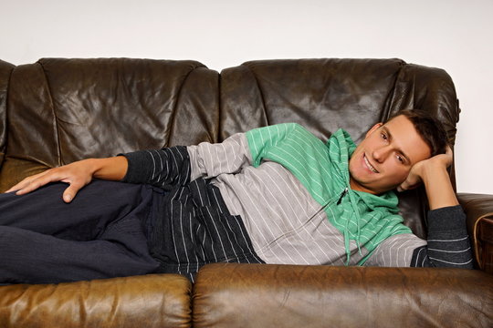 Young smiling man lying on couch relaxes