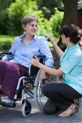 Female caregiver talking with handicapped woman on wheelchair