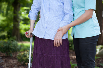 Nurse walking with a female patient with a crutch