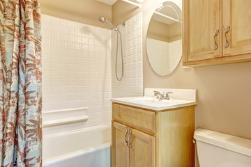 Light beige bathroom with wooden cabinets and floral curtain