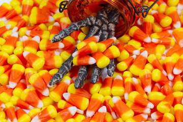 Scary skeleton hand coming out jar giving candy corn