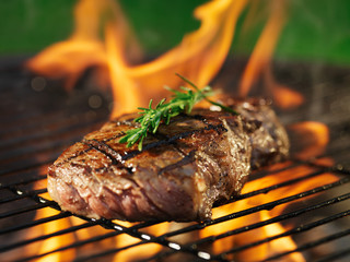 steak with flames on grill with rosemary