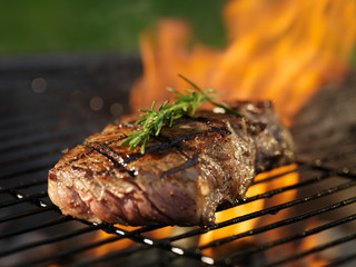 steak with flames on grill with rosemary