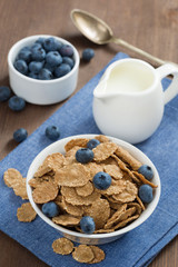 Fototapeta na wymiar wholegrain flakes with blueberries and milk, vertical