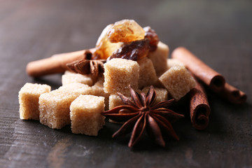Brown sugar cubes and reed sugar, spices on wooden background